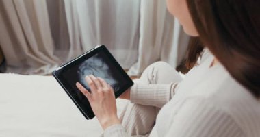 Hamile bir kadın, hastanede karnının yakın plan fotoğrafını çeker ve tabletindeki görüntüye hayran kalır..