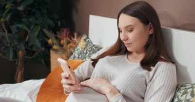 20 'li yaşlarının sonundan 30' lu yaşlarının başına kadar çekici, genç bir kadın yatakta uzanıyor ve dokunarak ve sesiyle bebeğiyle bağ kuruyor..