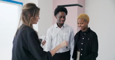 Yürek ısıtan bir anda sarışın bir emlakçı, yeni bir evin anahtarını mutlu bir Afrikalı çifte teslim ederken aynı zamanda ev sahibi olmanın hayalini kuruyor..