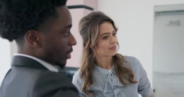 Kendine güvenen Afrikalı Amerikalı emlakçı sarışın kadın müşterilere yatırım fırsatları sunuyor..