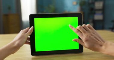 Video, oturma odasındaki koltukta rahat bir şekilde oturan bir kadını elinde tablet tutarken yakalıyor. Ekranda canlı yeşil bir maket görünüyor. Bu da cihazı aktif olarak kullandığını gösteriyor..