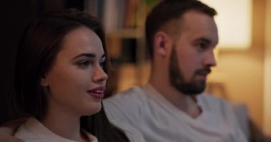 Çekici bir erkek ve çekici bir genç kadın sessizce oturup duygusal dramı izleyerek gözyaşlarını sildiklerini ve rahat bir odaklanma için birbirlerine yakın çekim yaptıklarını gösterir..