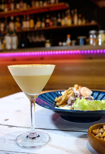 Pisco ve kızarmış mısırla birlikte mavi bir tabakta servis edilen Peru ceviche 'si.