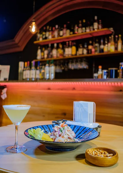 Pisco ve kızarmış mısırla birlikte mavi bir tabakta servis edilen Peru ceviche 'si.