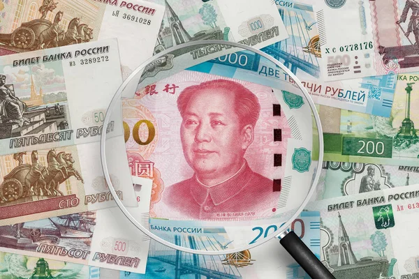 Chinese yuan and Russian ruble banknotes. Russia and China collaboration. View through magnifying glass