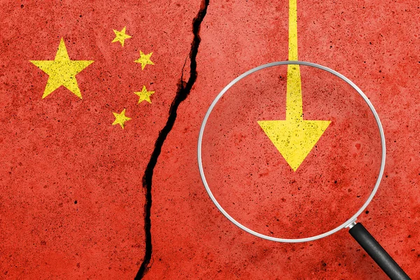 China flag painted on a cracked concrete background. China finance, real estate and debt crisis. China economic collapse. View through magnifying glass