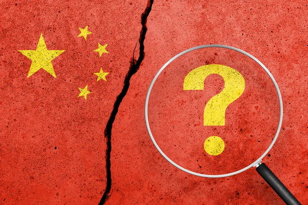 China flag painted on a cracked concrete background. China finance, real estate and debt crisis. China economic collapse. View through magnifying glass