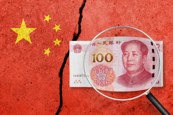 China flag painted on a cracked concrete background. China finance, real estate and debt crisis. China economic collapse. 100 yuan view through magnifying glass