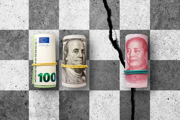 100 US dollars, hundred euros and 100 yuan banknotes on cracked concrete chess desk. Yuan is the currency of the China. United States, Europe Union trade war vs China