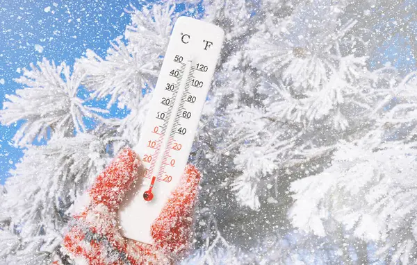 White celsius and fahrenheit scale thermometer in hand. Ambient temperature minus 28 degrees celsius