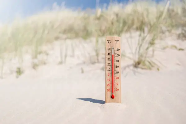 Wooden celsius and fahrenheit scale thermometer in the sand. Air temperature plus 41 degrees
