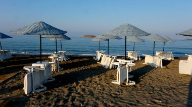 Şemsiyeler ve kumsalda güneşlenenler.