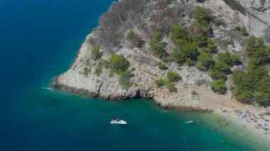 Dağlar ve ormanlar arasında güzel bir sahil. Hırvatistan. Makarska Riviera. Temiz mavi su ve çam aromalı Adriyatik Denizi gölü. İnsansız hava aracı videosu. Tatilde. Bir sürü insan. Nugal Plajı