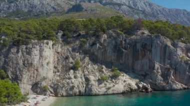 Çam ormanları ve Biokovo dağları ile kaplı kayaları gören bir dronun hava fotoğrafçılığı. Şehrin telaşından ve telaşından uzaklaşmak için güzel ve huzurlu bir yer..