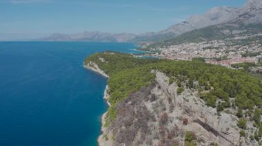 Makarska şehrinin panoramasıyla kıyı uçurumları üzerinde uçan bir İHA 'nın havadan çekilmiş fotoğrafı. Hırvatistan