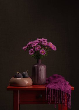Kırmızı bir masada koyu pembe astıcılar. Yakınlarda mor bir mendil var, iki tane olgun mavi incir. Karanlık arka plan. Bir buket çiçek. Durgun hayat. Keder, üzüntü, özlem, elveda. Vitaminler. Yansıma.