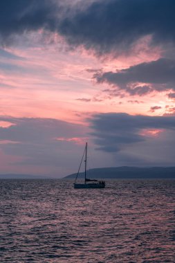 Sailboat in the Adriatic Sea during a picturesque red sunset. Yacht in the open sea. Cruise travel.