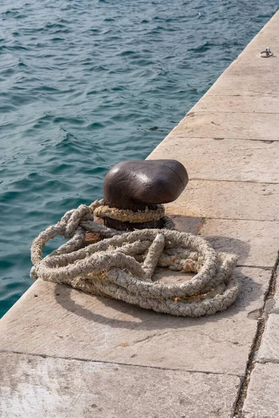 Tangled nautical rope tied to a docking link against the backdrop of the sea