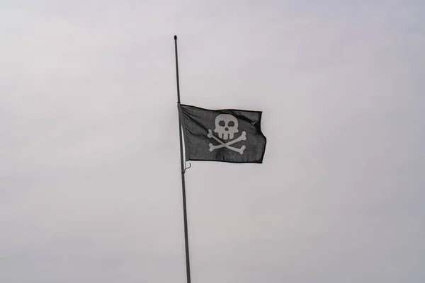 海盗的旗帜在灰蒙蒙的天空中飘扬 骷髅和交叉的骨头 — 图库照片