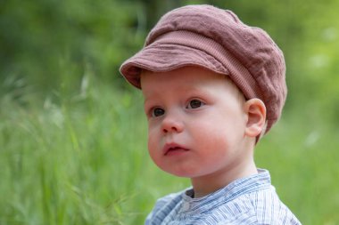 Bir doğa parkında güneşli bir yaz gününün tadını çıkaran yakışıklı ve mutlu küçük bir çocuğun portresi. Çocuklar için aktif eğlence kavramı ve doğada olmanın keyfi..