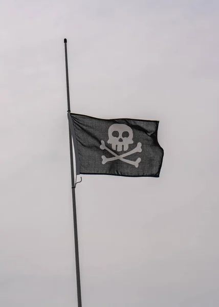 一般的な海賊旗は 空に対して風になびく 頭蓋骨と骨 — ストック写真