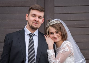 Genç ve modern bir çiftin portresi. Gelin ve damat yakın çekim. Kahverengi panjurlu arka plan. düğün, aşk, yeni aile