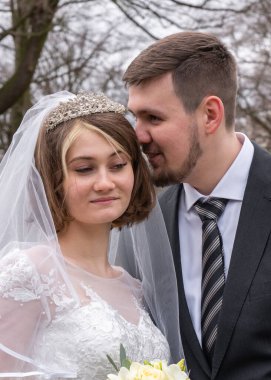 Damat geline doğru eğildi ve onun kulağına bir şey söyledi. Gelin gülümsüyor. Düğün için. Gelin ve damadın yakın plan portresi..