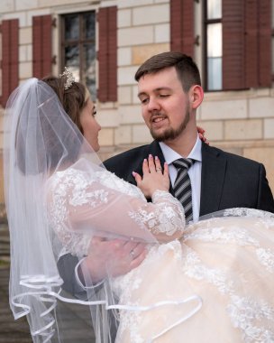 Damat genç gelini nazikçe kollarında tutuyor. Yakın plan. Aşk 