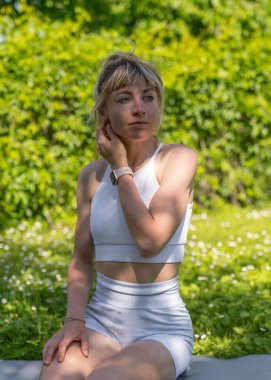 A young, athletic girl is engaged in stretching  in the fresh air. Rest after class. Beauty and health. Active lifestyle. Physical exercise. Fitness. Sport