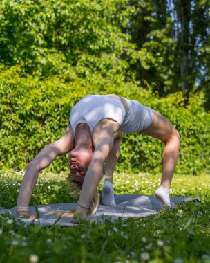 A young, athletic girl is engaged in stretching  in the fresh air. Beauty and health. Active lifestyle. Physical exercise. Fitness. Sport