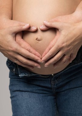 Anne babanın elleri hamile annenin karnında kalp yapıyor.