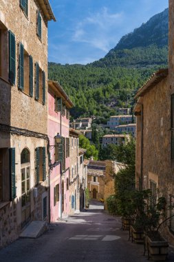 İspanya 'nın Mallorca kentindeki Deia adlı küçük bir sahil köyünün çarpıcı manzarası. Yeşil ağaçlarla çevrili tepelerdeki teraslarda geleneksel evler. İspanyol turizm merkezleri.