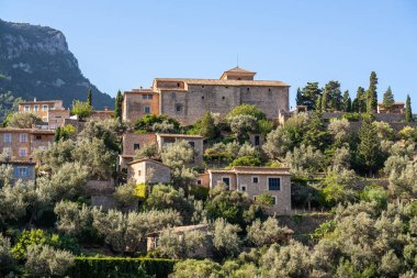 İspanya 'nın Mallorca kentindeki Deia adlı küçük bir sahil köyünün çarpıcı manzarası. Yeşil ağaçlarla çevrili tepelerdeki teraslarda geleneksel evler. İspanyol turizm merkezleri.
