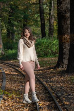 Sonbahar yürüyüşü. Kadın portresi. Mutlu bir kız parkta bir ağacın yanında duruyor ve başka yere bakıyor.. 