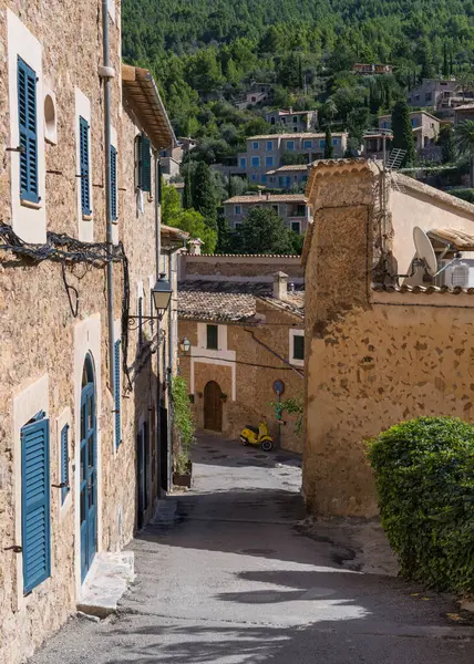 İspanya 'nın Mallorca kentindeki küçük Deia kıyı köyünün çarpıcı manzarası. Geleneksel evler, dar sokaklar, sokağın sonunda sarı bir motosiklet var. İspanya 'da turistik yerler.. 