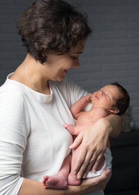 Sevgi dolu bir anne yeni doğan bebeğine evde bakar. Kollarında bir çocuk tutan mutlu bir annenin parlak portresi. Anne küçük oğluna sarılıyor..