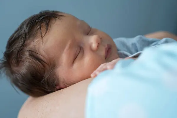 Anne yeni doğmuş bir çocuğu kucağına alır, bebek tatlı tatlı uyur. Annenin elleri ve bebeğin yakın çekimi. Bebek sağlığı ve gelişimi. Bir çocuğun doğumu ve ebeveynlerin sevgisi..