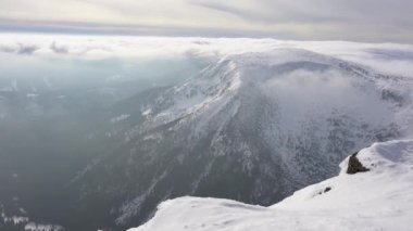 Karla kaplı dağ tepelerinin manzarası. Bulutlar. Kışın dağlarda güneşli bir gün. Polonya 'da Sniezka. Polonya 'daki Dev Dağlar' ı gösteren video. Karkonosze Ulusal Parkı. Bohem Massif