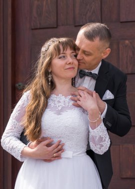 Gelin ve damat evlendikten sonra basamaklarda dikiliyorlar. Damat usulca eğildi gelini öpmek için.