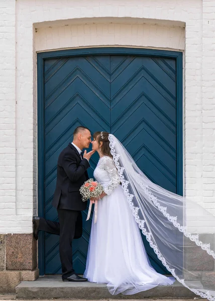 Love, wedding and married couple kiss against the background of blue doors in honor of their romantic marriage. Traditionally, the bride and groom kiss after the ceremony.