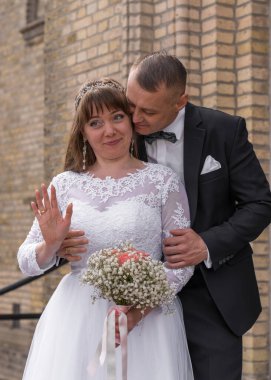 Gelin ve damat evlendikten sonra basamaklarda dikiliyorlar. Damat usulca eğildi gelini öpmek için