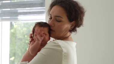 Sevgi dolu bir anne yeni doğan bebeğine bakar. Annem kucağında ağlayan bir bebek tutuyor. Anne küçük, yeni doğmuş oğluna sarılıyor.