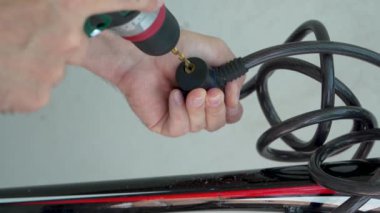 Videoda adamın elleri görünüyor. Bir adam kilitli bisiklet kilidini delmek için elektrikli matkap kullanıyor. servis, yardım
