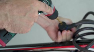 Videoda adamın elleri görünüyor. Bir adam kilitli bisiklet kilidini delmek için elektrikli matkap kullanıyor. servis, yardım.