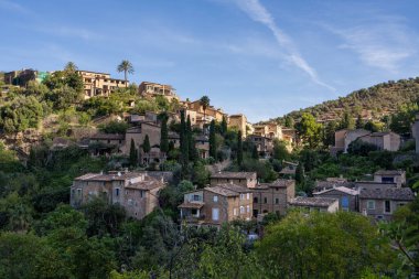 İspanya 'nın Mallorca kentindeki küçük Deia kıyı köyünün çarpıcı manzarası. Yeşil ağaçlarla çevrili tepelerde geleneksel evler. İspanya 'da turistik yerler. Balear Adaları. 