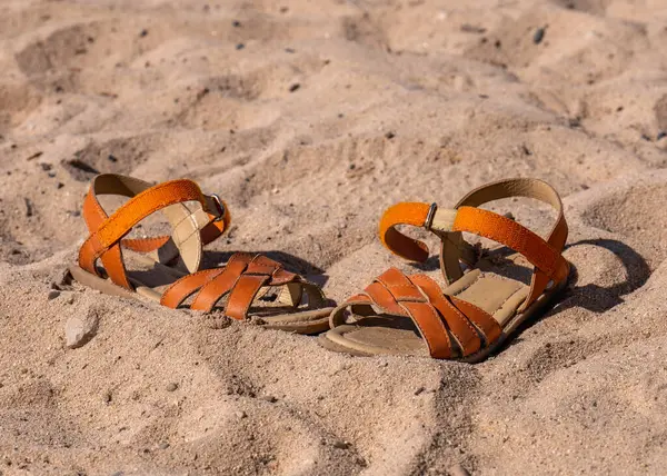 Children\'s, orange shoes on the beach. Sand. Sea. Rest. Vacation.