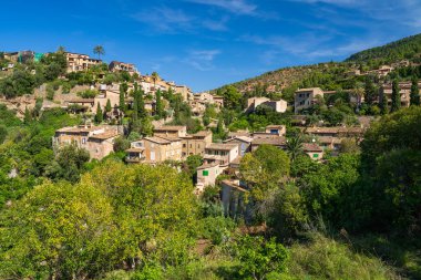 İspanya 'nın Mallorca kentindeki küçük Deia kıyı köyünün çarpıcı manzarası. Yeşil ağaçlarla çevrili tepelerde geleneksel evler. İspanya 'da turistik yerler. Balear Adaları.
