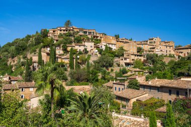 İspanya 'nın Mallorca kentindeki küçük Deia kıyı köyünün çarpıcı manzarası. Yeşil ağaçlarla çevrili tepelerde geleneksel evler. İspanya 'da turistik yerler. Balear Adaları.