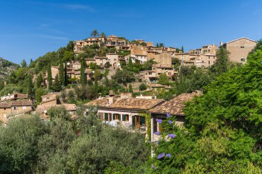 İspanya 'nın Mallorca kentindeki küçük Deia kıyı köyünün çarpıcı manzarası. Yeşil ağaçlarla çevrili tepelerde geleneksel evler. İspanya 'da turistik yerler. Balear Adaları