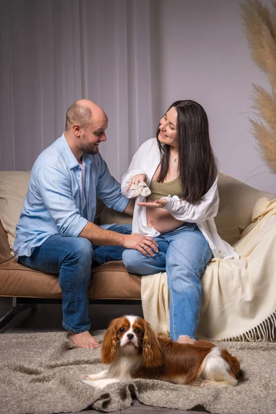 Bir aile bebek bekliyor. Bir adam yerde oturuyor, çıplak göbekli hamile bir kadın kanepede oturuyor. O, ellerinde küçük çoraplar tutuyor ve onların yanında bir köpek oturuyor. Şövalye Kral Charles Cocker Spaniel